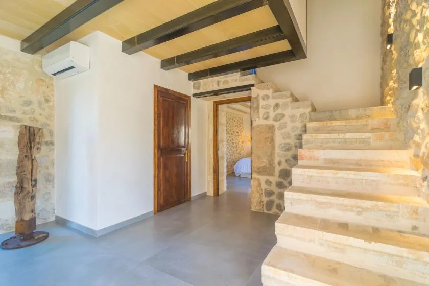 A stone staircase rises beside a wooden door in a bright interior.