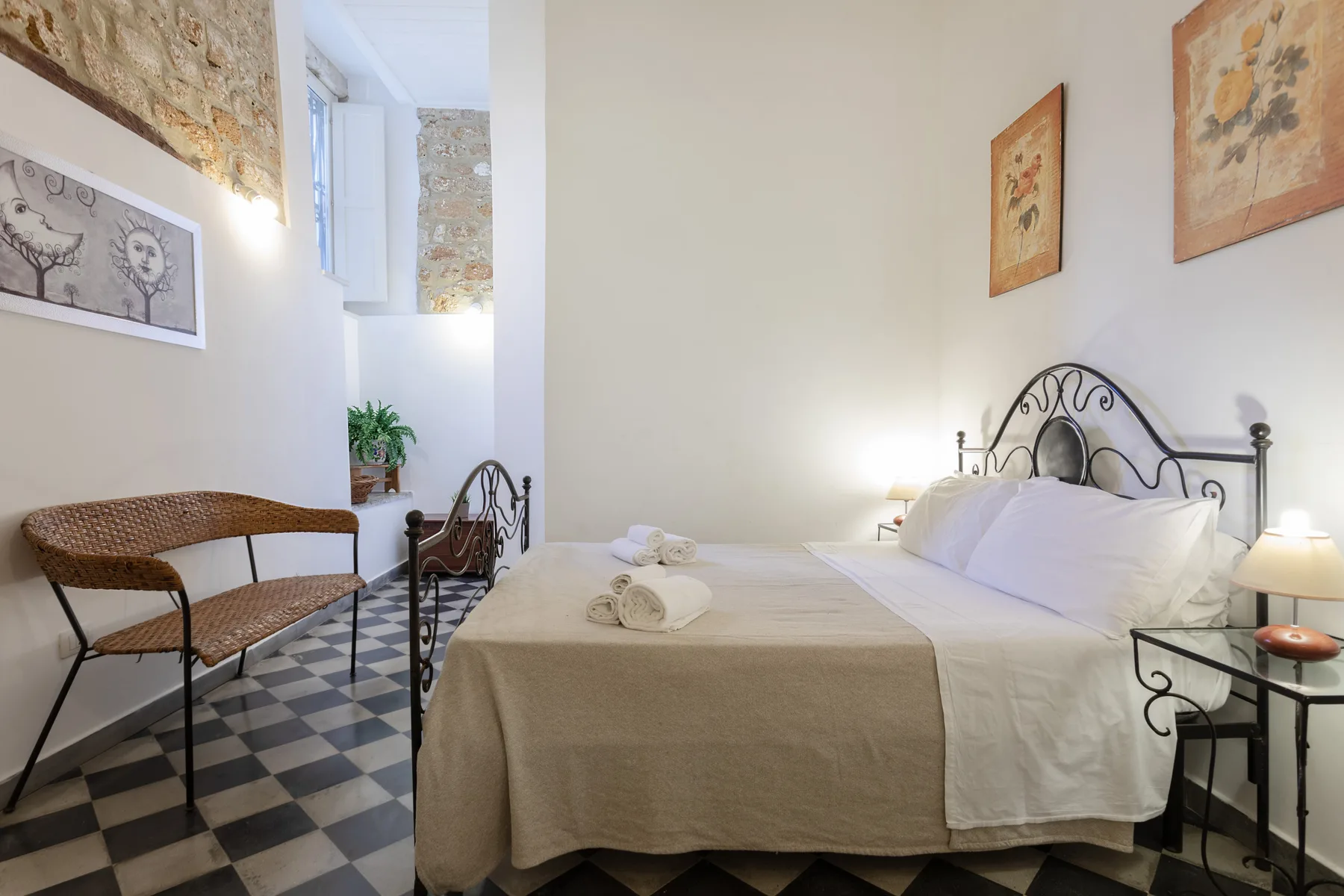 Un dormitorio con una cama, ropa de cama blanca y una pequeña zona de estar.