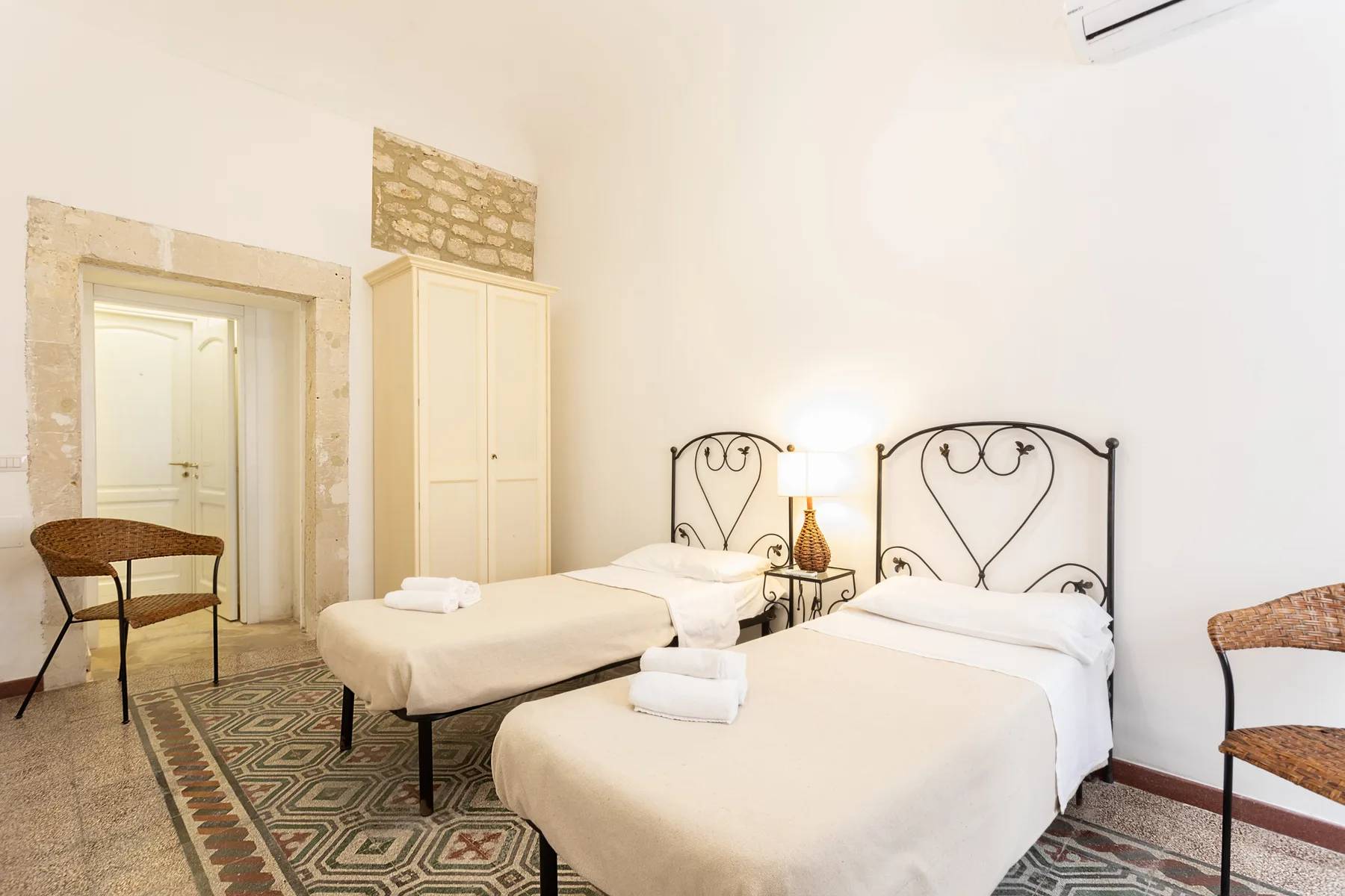 Un dormitorio luminoso con dos camas y un armario junto a la puerta.