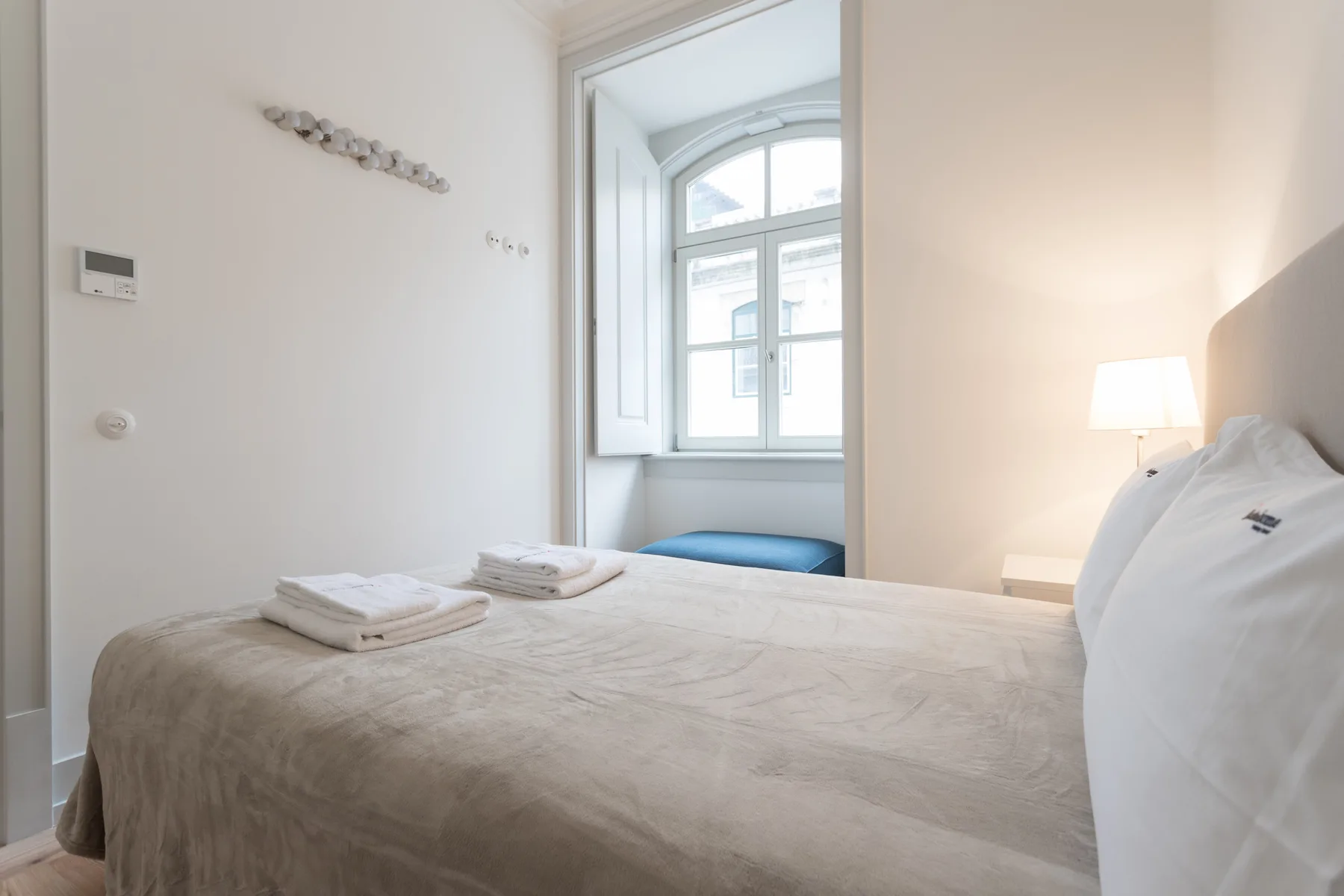 A bright bedroom with a neatly made bed and a large window.