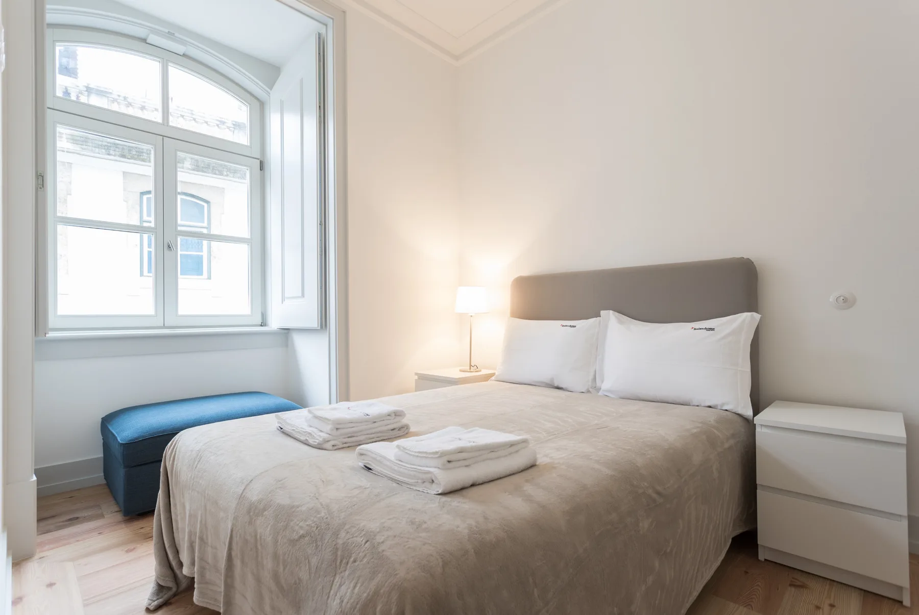 A bedroom with a neatly made bed and a large window.