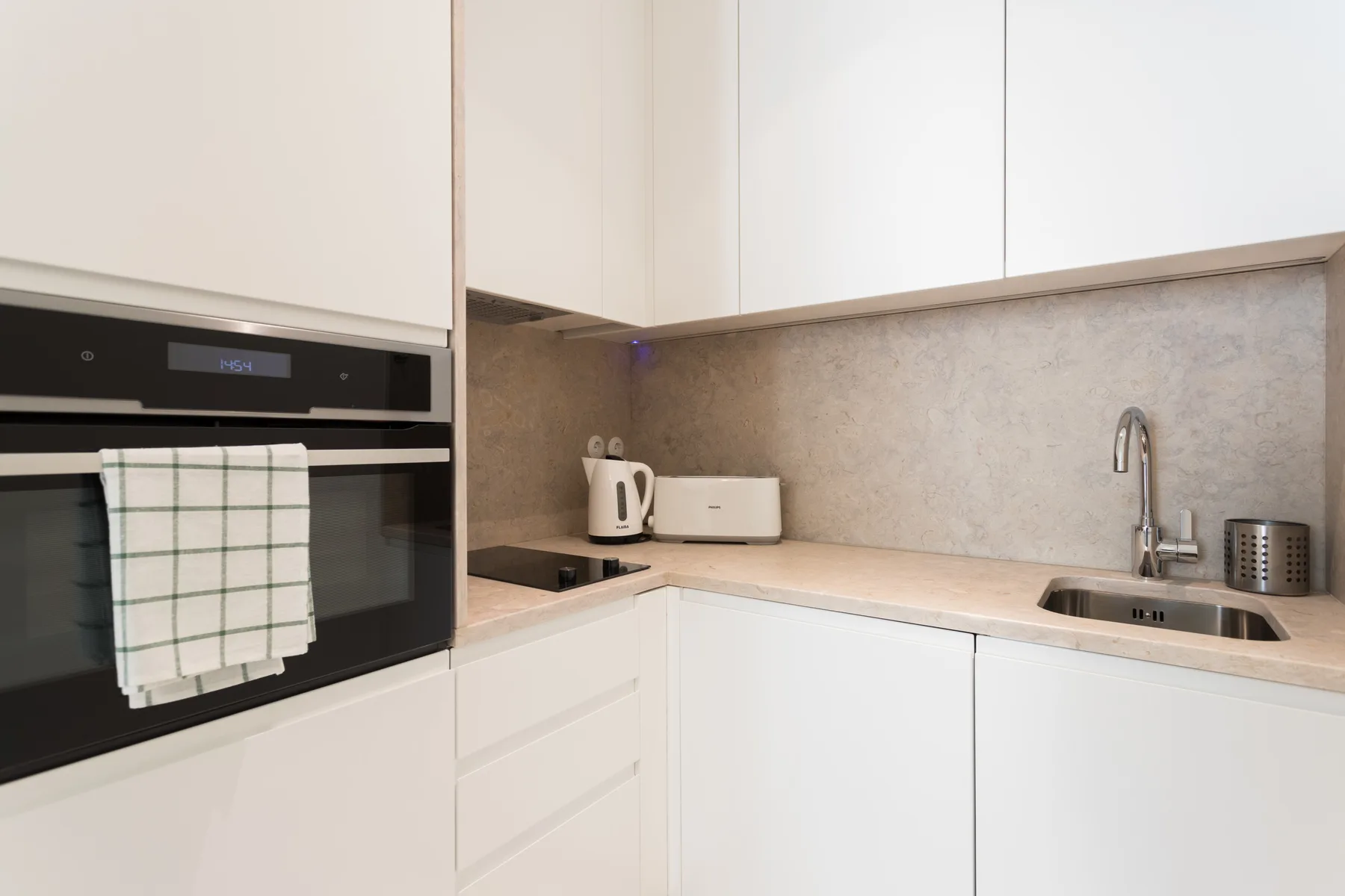 A compact kitchen with white cabinets, countertop appliances, and a sink.