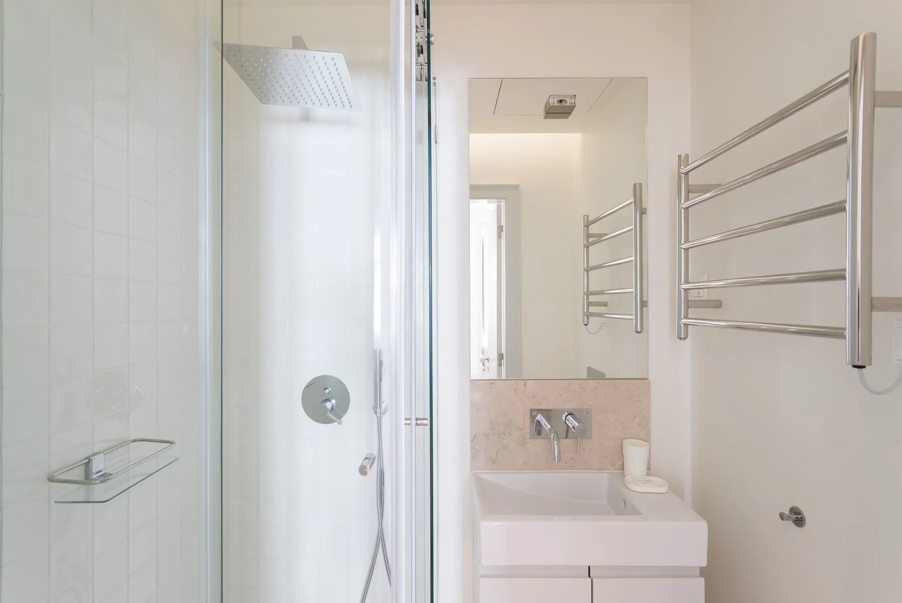 A bright bathroom with a glass shower and wall-mounted towel rack.
