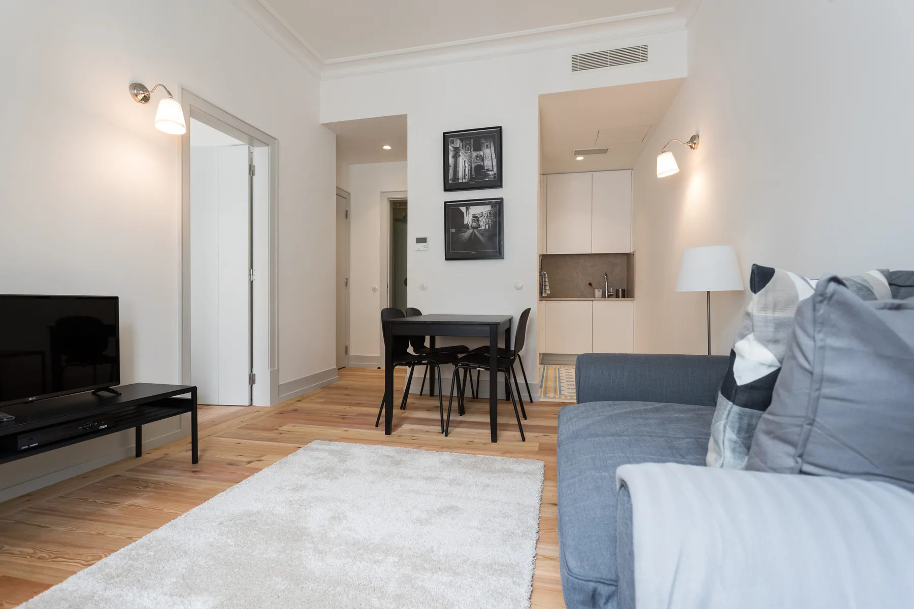 A bright living and dining area with a sofa, table, and compact kitchen.