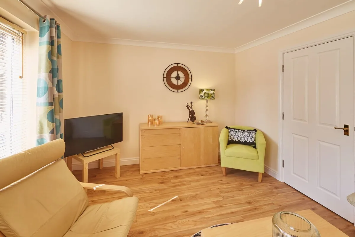 A living room with seating, a television, and a wooden cabinet.