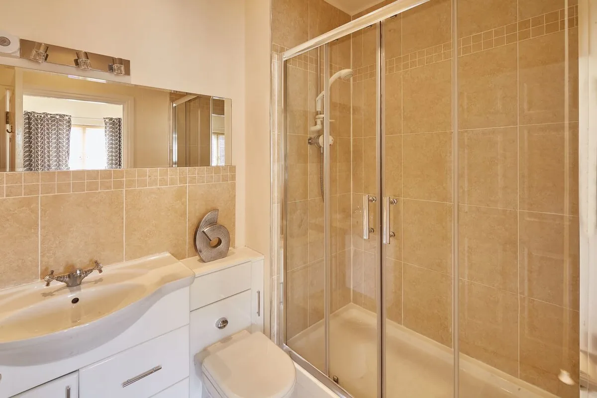 A bathroom with a sink and a glass-enclosed shower.