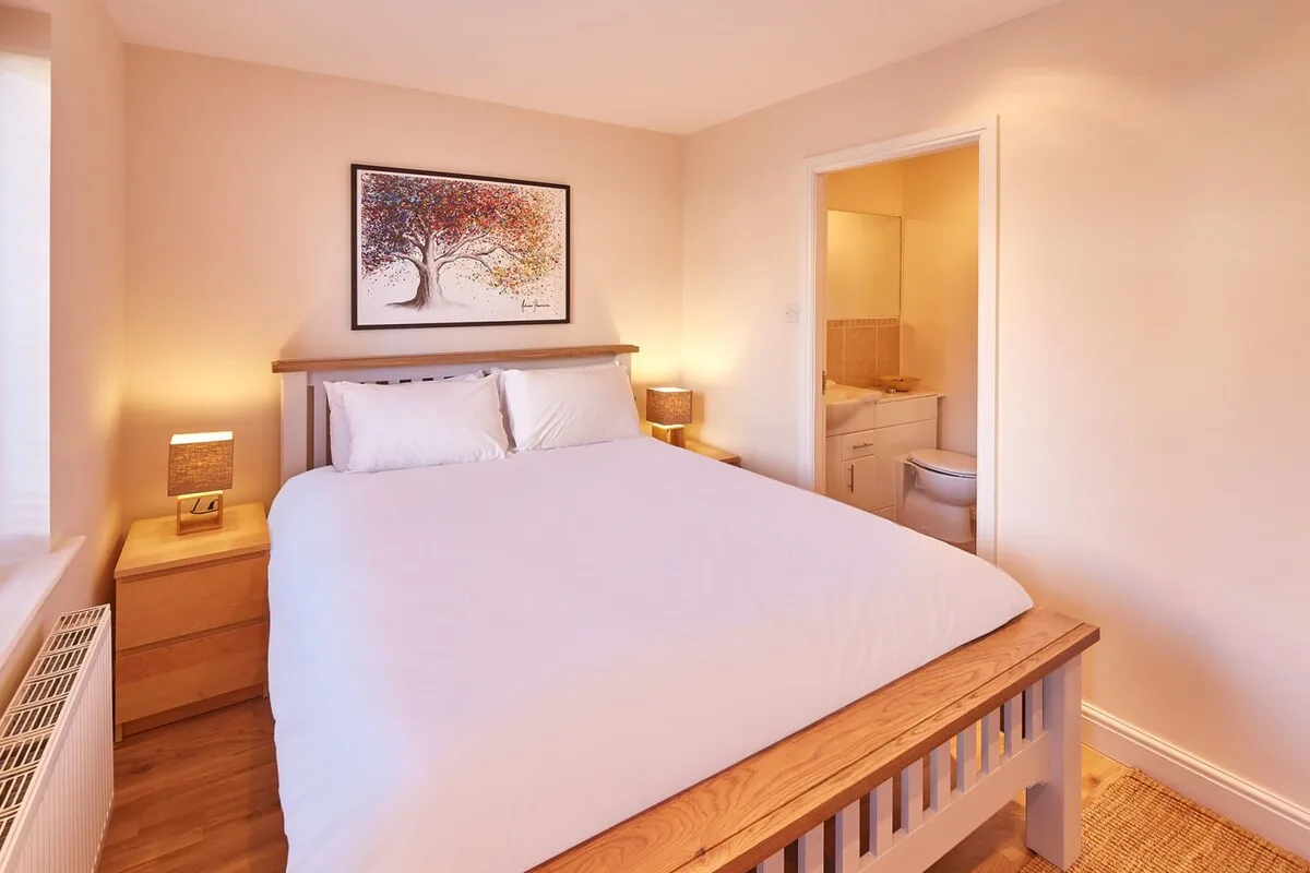 A bedroom with a neatly made bed and an open doorway to a bathroom.