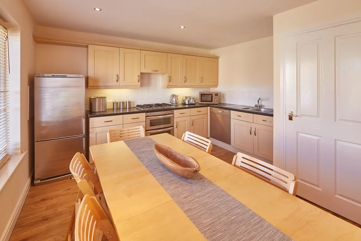 A kitchen and dining area with light wood cabinets and a long table.