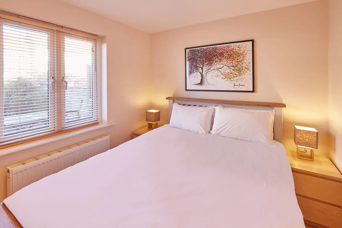 A bedroom with a neatly made bed and framed artwork above the headboard.