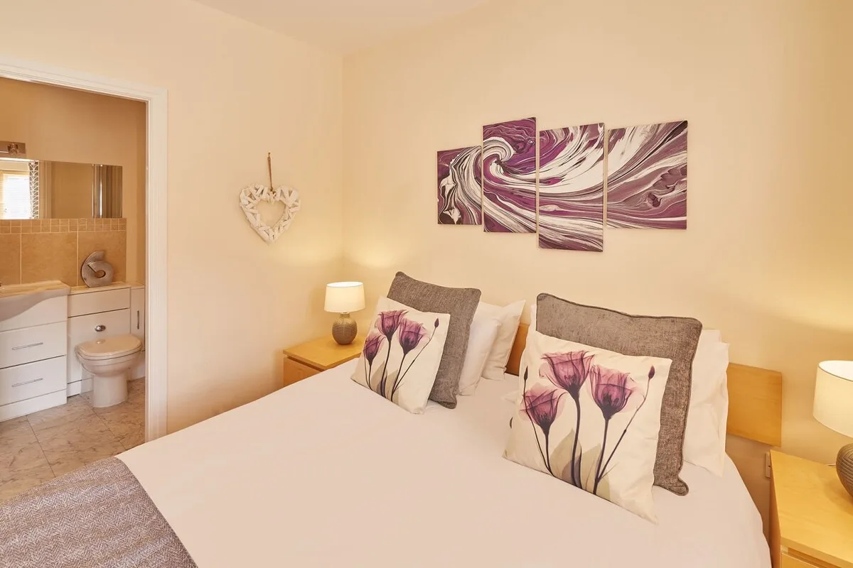 A bedroom with a neatly made bed and floral accent pillows.