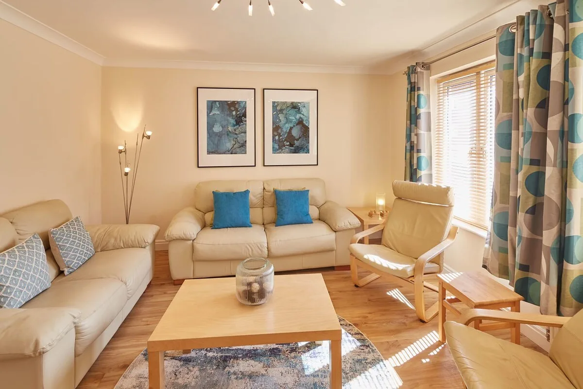 A bright living room with seating around a wooden coffee table.