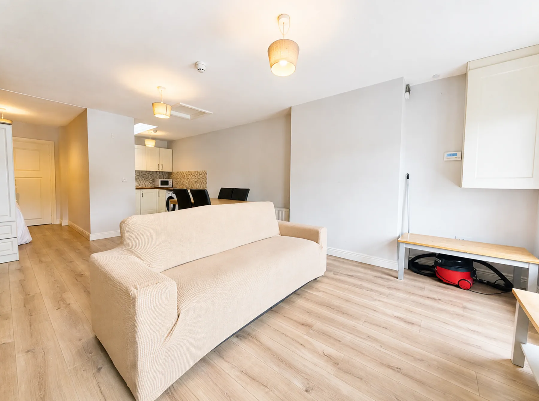 A bright living area with seating and a kitchenette in the background.