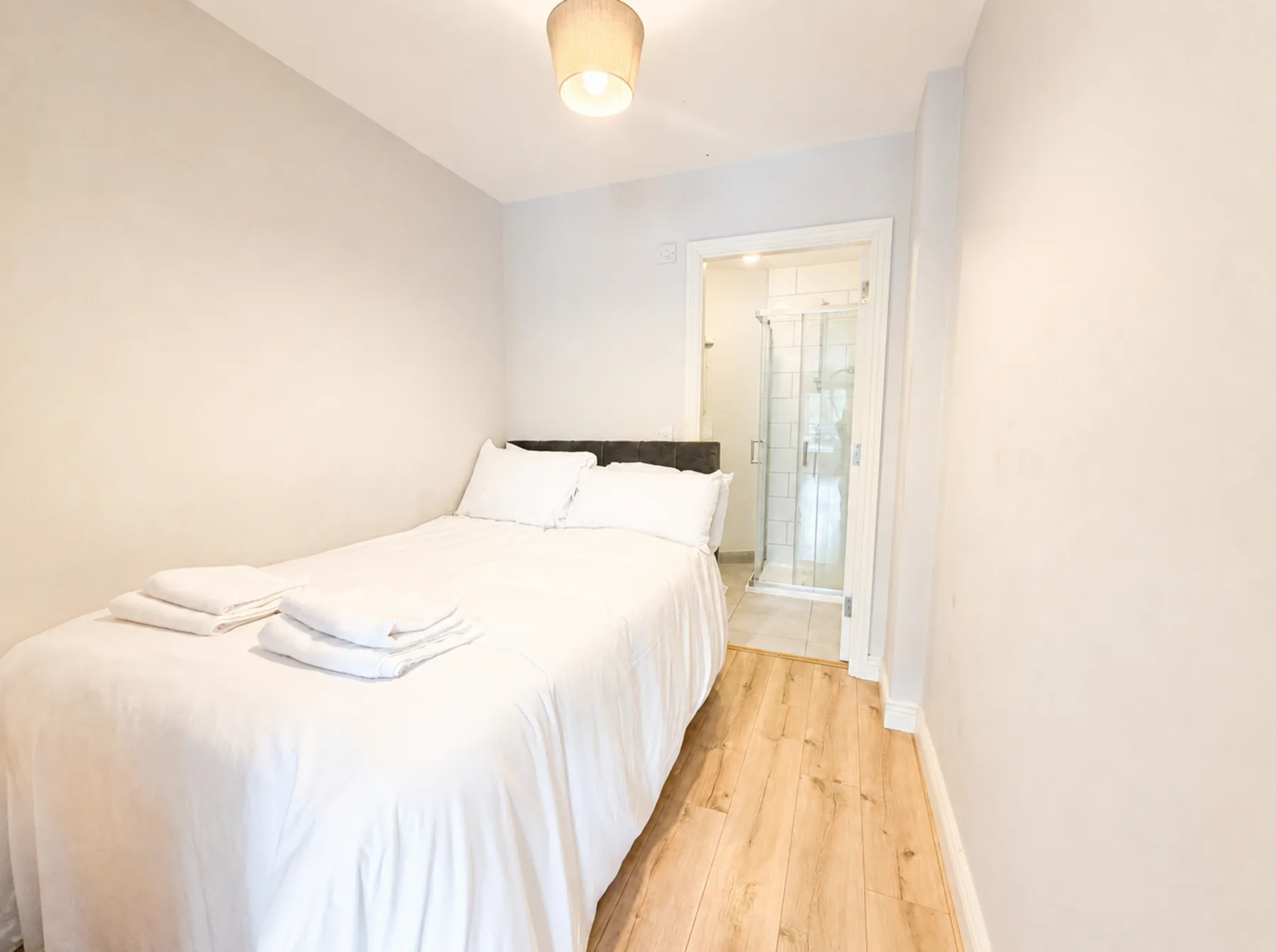 A bedroom with a bed and an adjoining shower area.