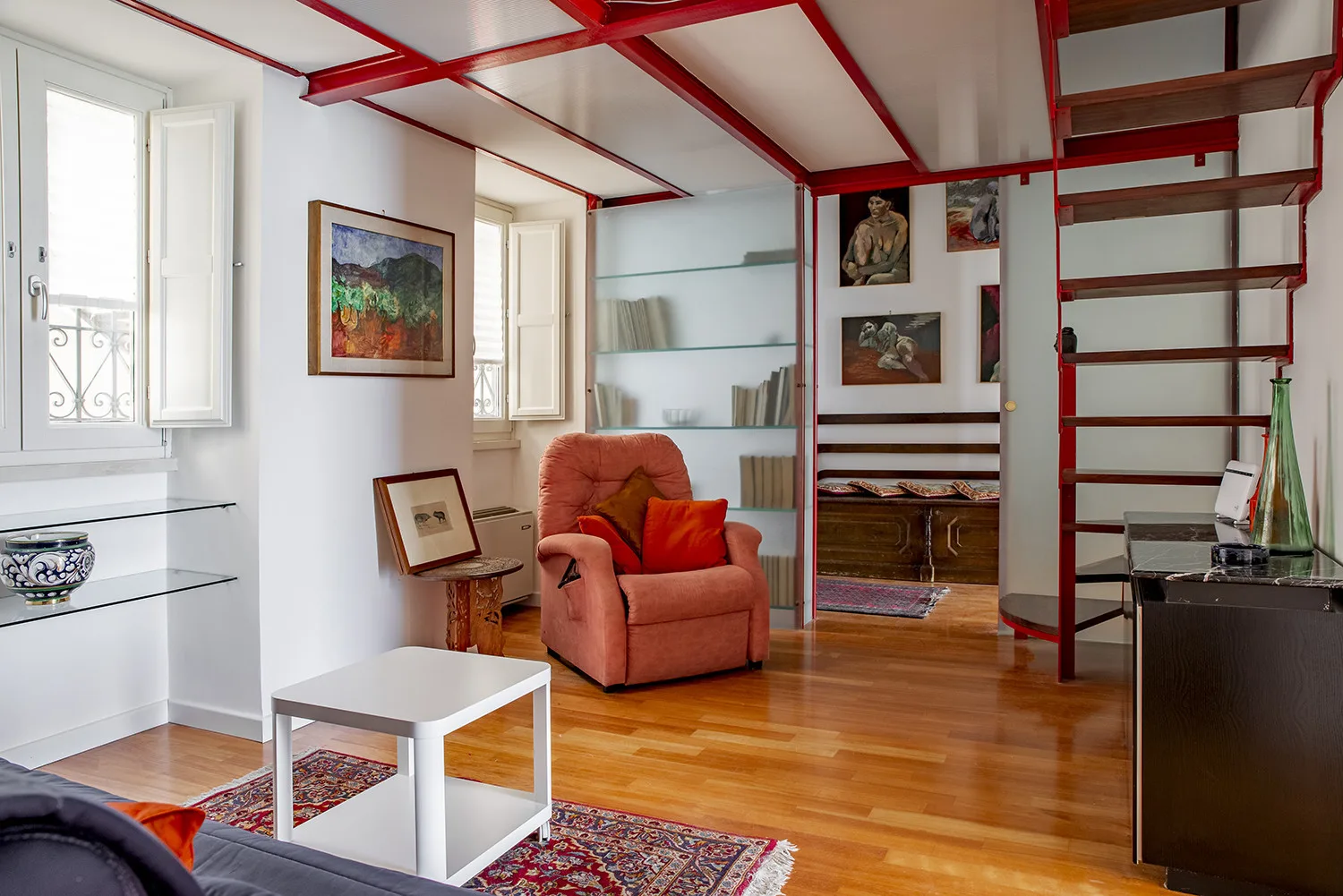 A living room with an armchair, coffee table, and exposed red ceiling beams.
