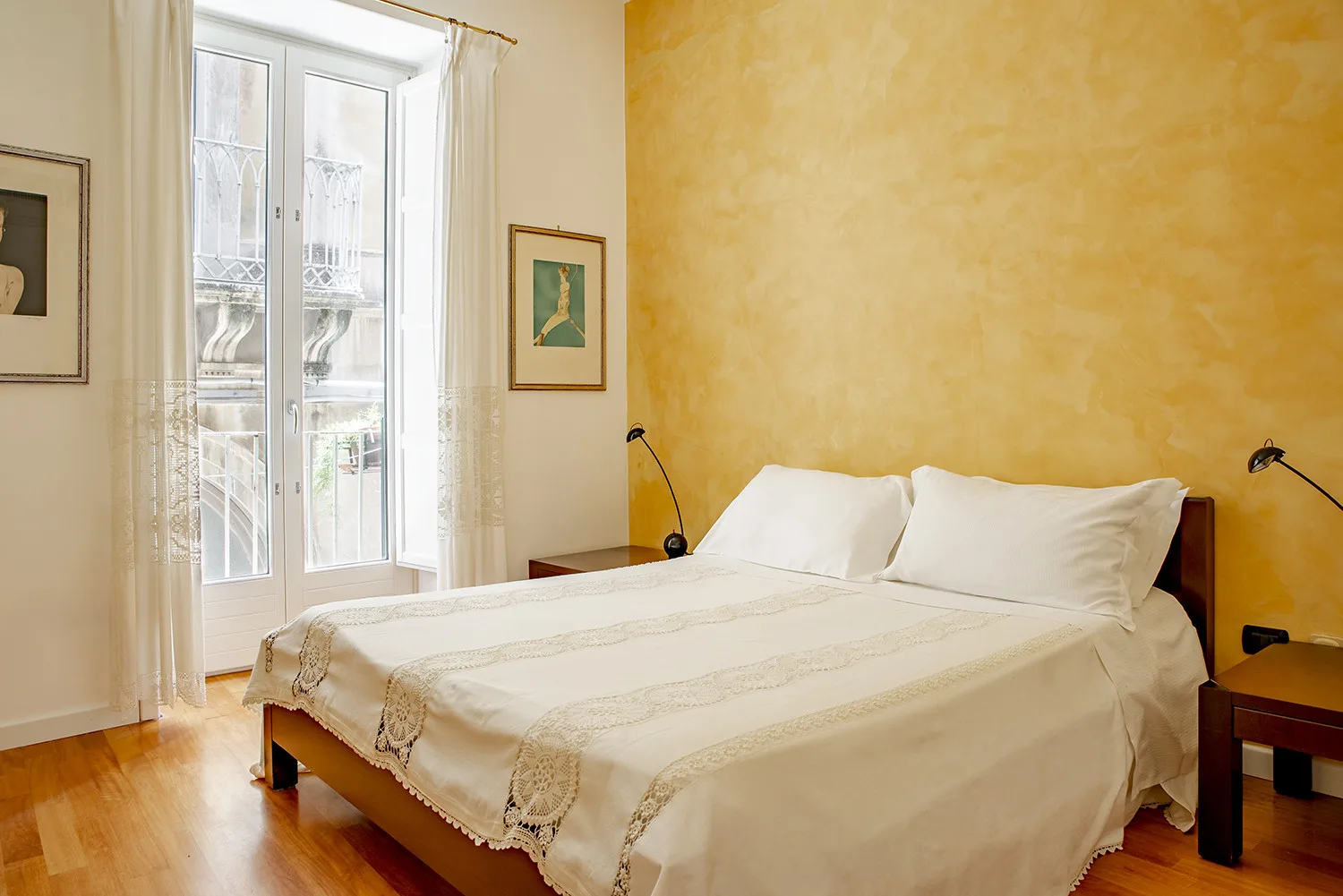 A bedroom with a double bed, white bedding, and a large window.