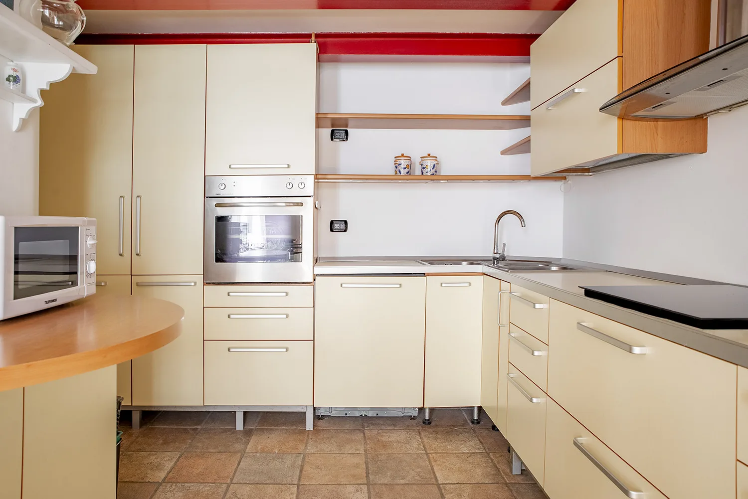 A bright kitchen with cream cabinets, a countertop, and a sink.
