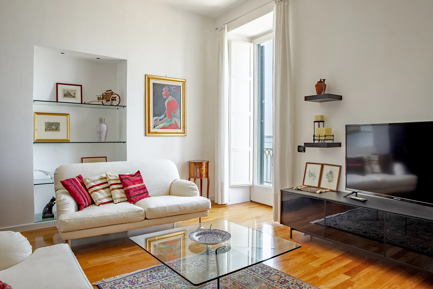 A living room with a sofa, glass coffee table, and television.