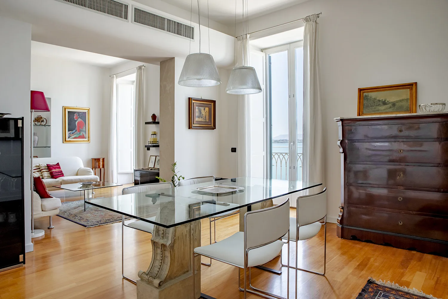 A bright dining area with a glass table and tall windows.