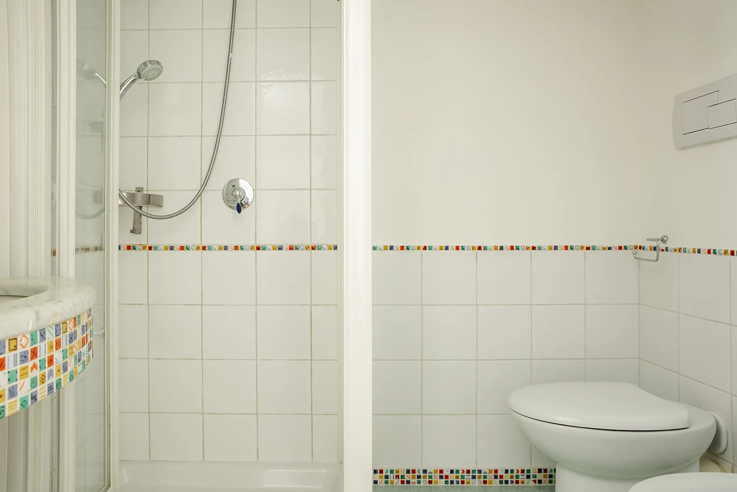 A tiled bathroom with a shower and toilet.