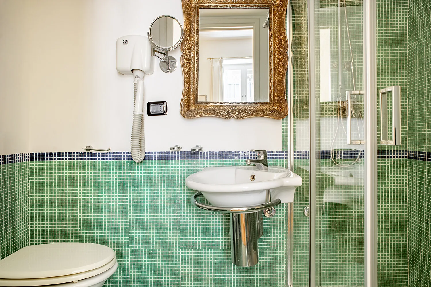 A tiled bathroom with a wall-mounted sink and glass shower enclosure.