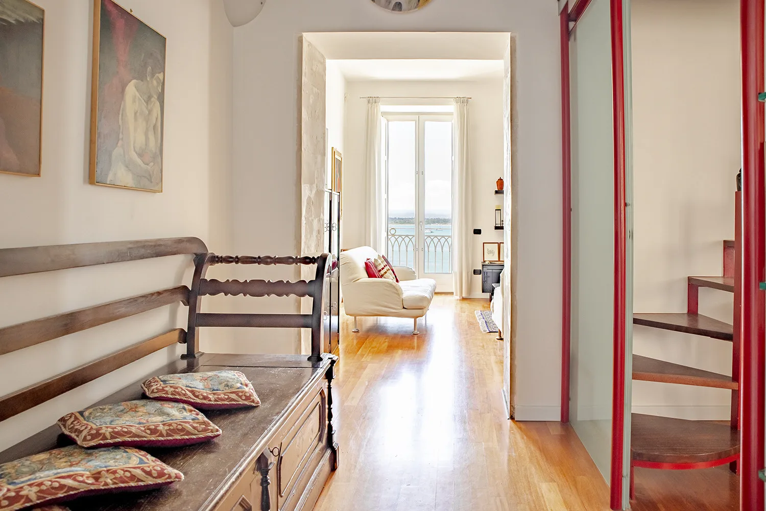 A bright hallway with a wooden bench and a distant balcony door.