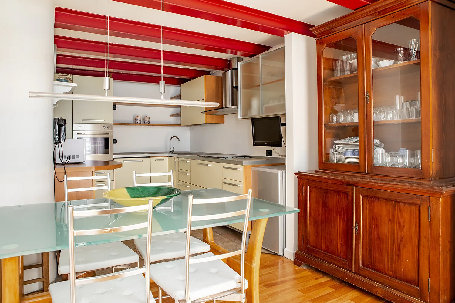 A kitchen and dining area with a glass table and wooden cabinets.