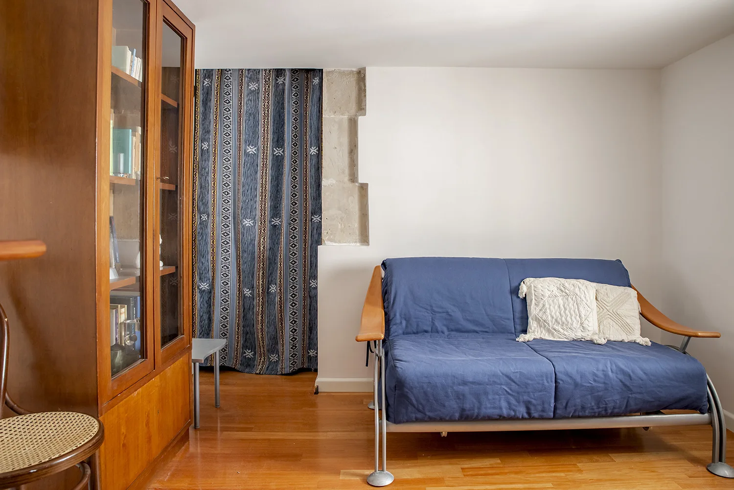 A sitting room with a blue sofa and patterned curtains.