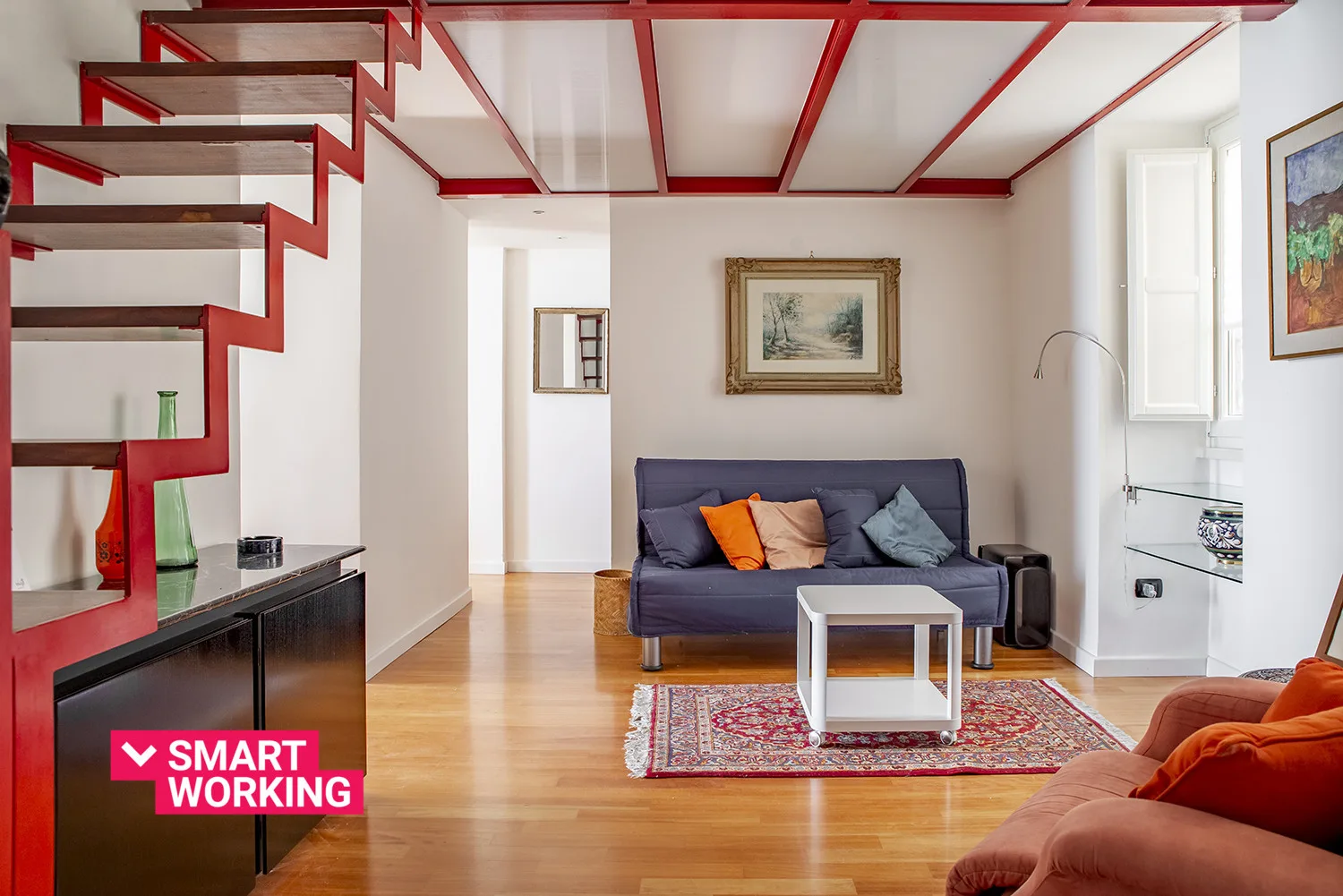 A living room with a sofa, coffee table, and red ceiling beams.