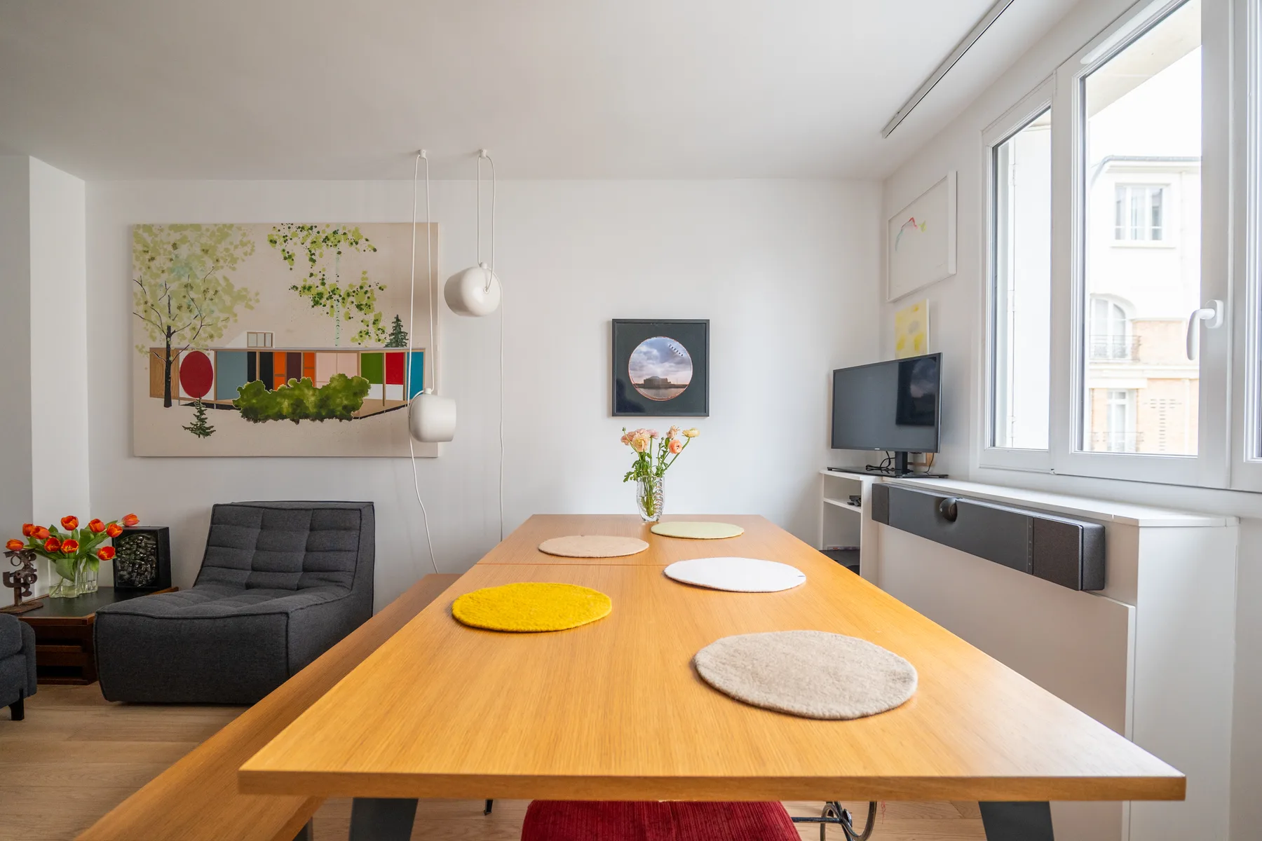 A bright dining area with a long wooden table and large windows.