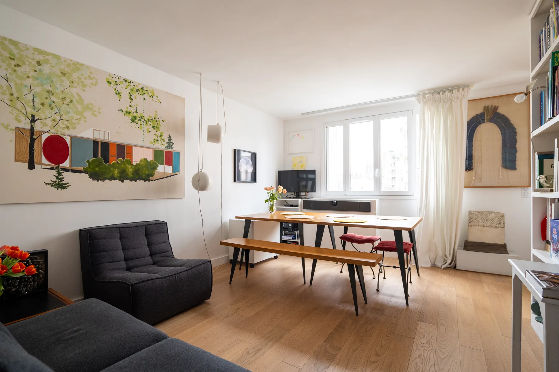 A bright living and dining area with a table, seating, and large windows.