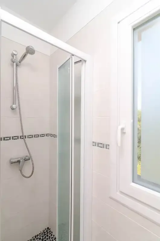 A bright bathroom with a shower and a large window.