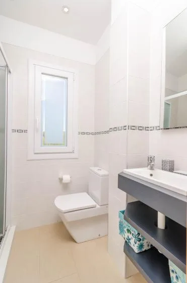 A bright bathroom with a window, toilet, and sink.