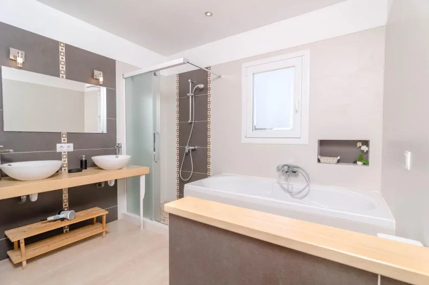 A bathroom with a bathtub, glass shower, and double sinks.