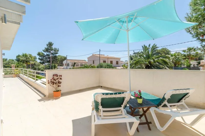 Una terraza soleada con asientos al aire libre y un toldo turquesa.
