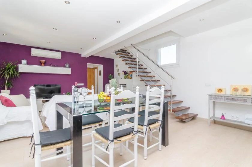 A bright open-plan living and dining area with a staircase and dining table.