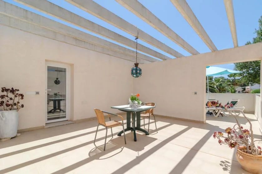 A sunlit covered patio with a dining table and an open view of the garden.