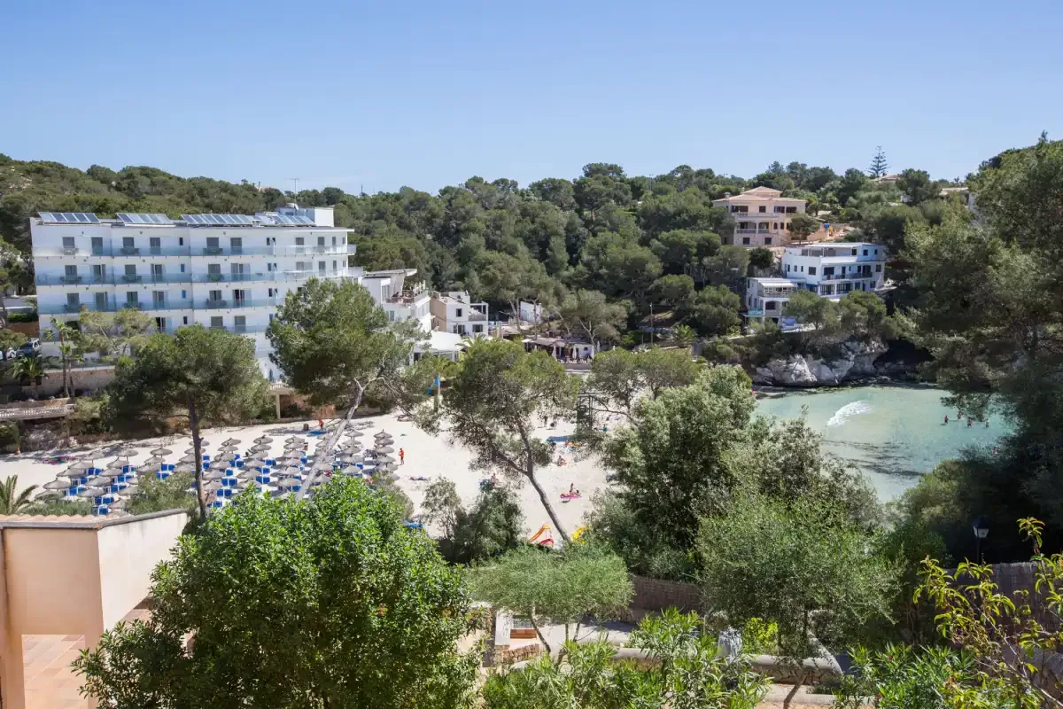 A coastal cove with waterfront buildings, trees, and a sandy beach.