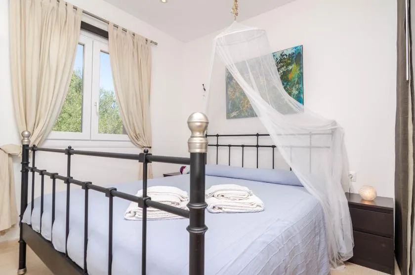 A bedroom with a metal-framed bed, pale bedding, and a canopy net.