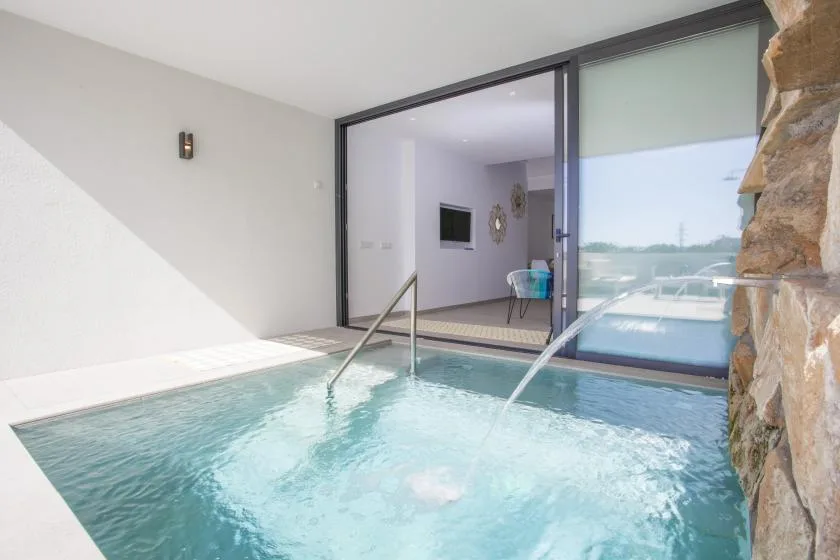 Una piscina interior junto a puertas corredizas de vidrio y una pared de piedra.