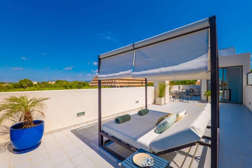 Una terraza soleada en la azotea con una cama de día a la sombra y asientos al aire libre.