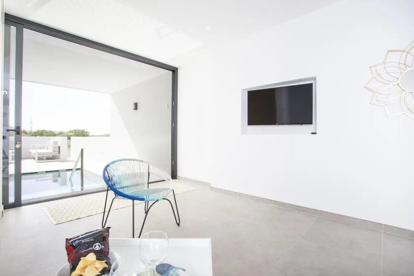 Una sala luminosa se abre a un patio, con un televisor en la pared.