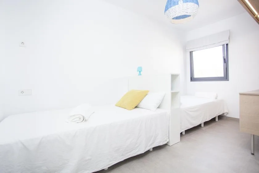 Un dormitorio luminoso con ropa de cama blanca y una ventana.