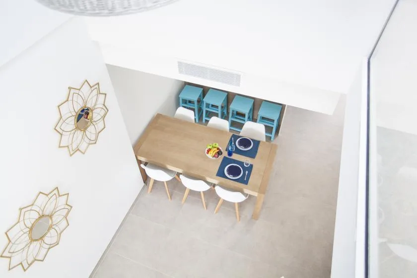 Un comedor luminoso con una mesa de madera y sillas turquesas.