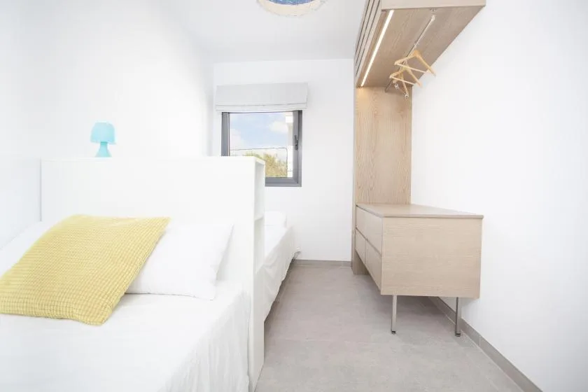 Un dormitorio luminoso con una cama y almacenamiento empotrado junto a la ventana.