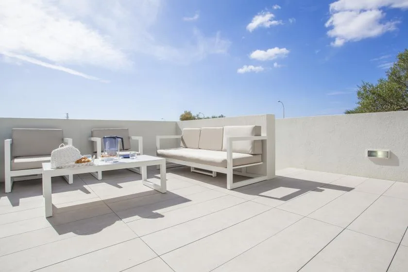 Una terraza en la azotea con asientos al aire libre y una mesa baja bajo un cielo azul.