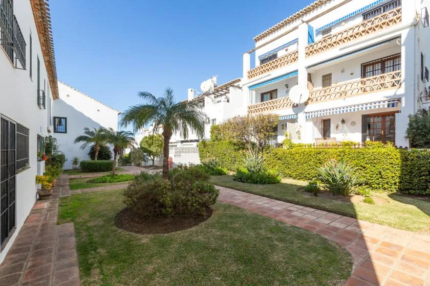 A landscaped courtyard with paved walkways and white apartment buildings.