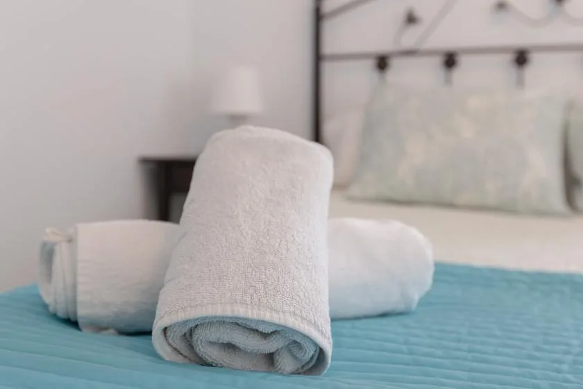 Rolled white towels rest on a blue bedspread.
