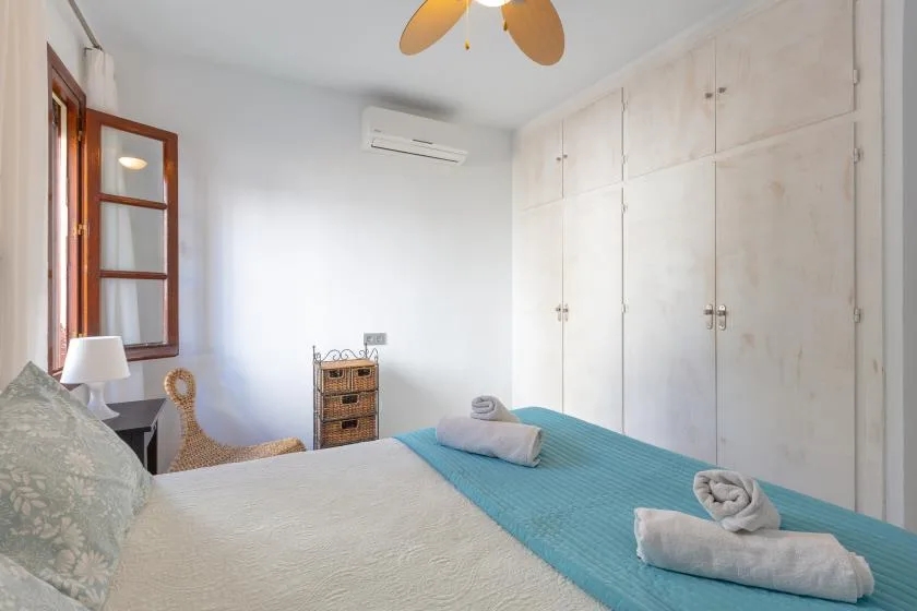 A bedroom with a bed, built-in cupboards, and a window.