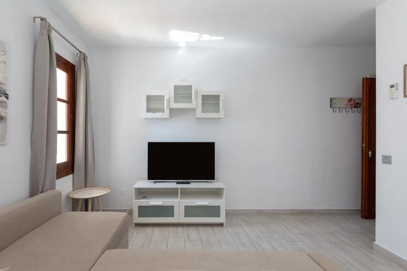 A bright living room with seating, a television, and a window.