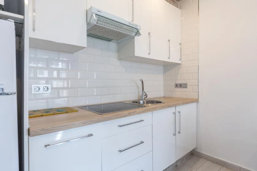 A bright kitchen with white cabinets, a tiled backsplash, and a countertop.